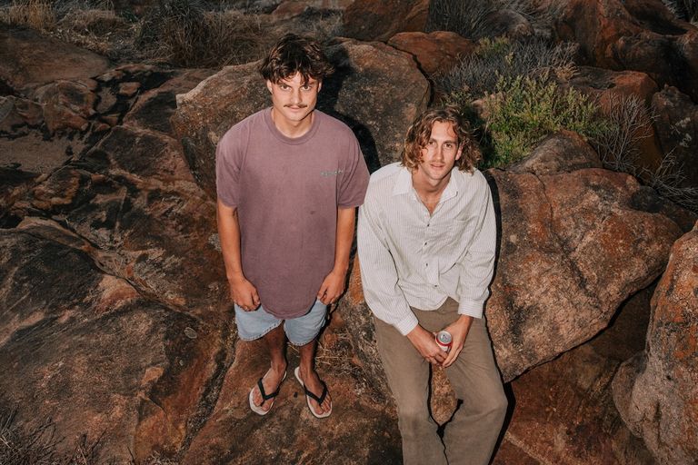 Australian duo Old Mervs posing outdoors on large rocky terrain, photographed by Annie Smith.
